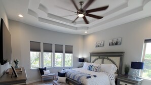 A bedroom with a bed, nightstands, a dresser, a ceiling fan, and large windows. - Hill Country Escape (Spring Branch)