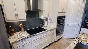 A modern kitchen with white cabinets, a black backsplash, stainless steel appliances, and a granite countertop. - Hill Country Escape (Spring Branch)