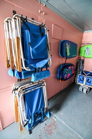 Un espacio de almacenamiento con varias maletas y bolsos, algunos con ruedas, frente a una pared rosa.