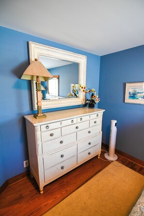 A white dresser with multiple drawers, a mirror above it, and a lamp on top.