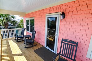 A covered porch with a red brick wall, a sliding glass door, and outdoor furniture. - Top Floor Suite of classic 1940's Beach Cottage with porch & partial ocean view. (Wrightsville Beach)