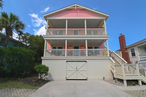 A two-story building with a balcony on the upper floor, a garage door, and a staircase leading to the entrance.