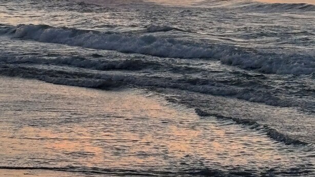 A pier extending into the ocean with waves crashing against it.
