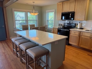 A kitchen with a central island, wooden cabinets, a microwave, and a stove.