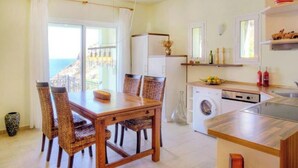 Une cuisine compacte avec un coin repas, un lave-linge et une vue sur la mer.