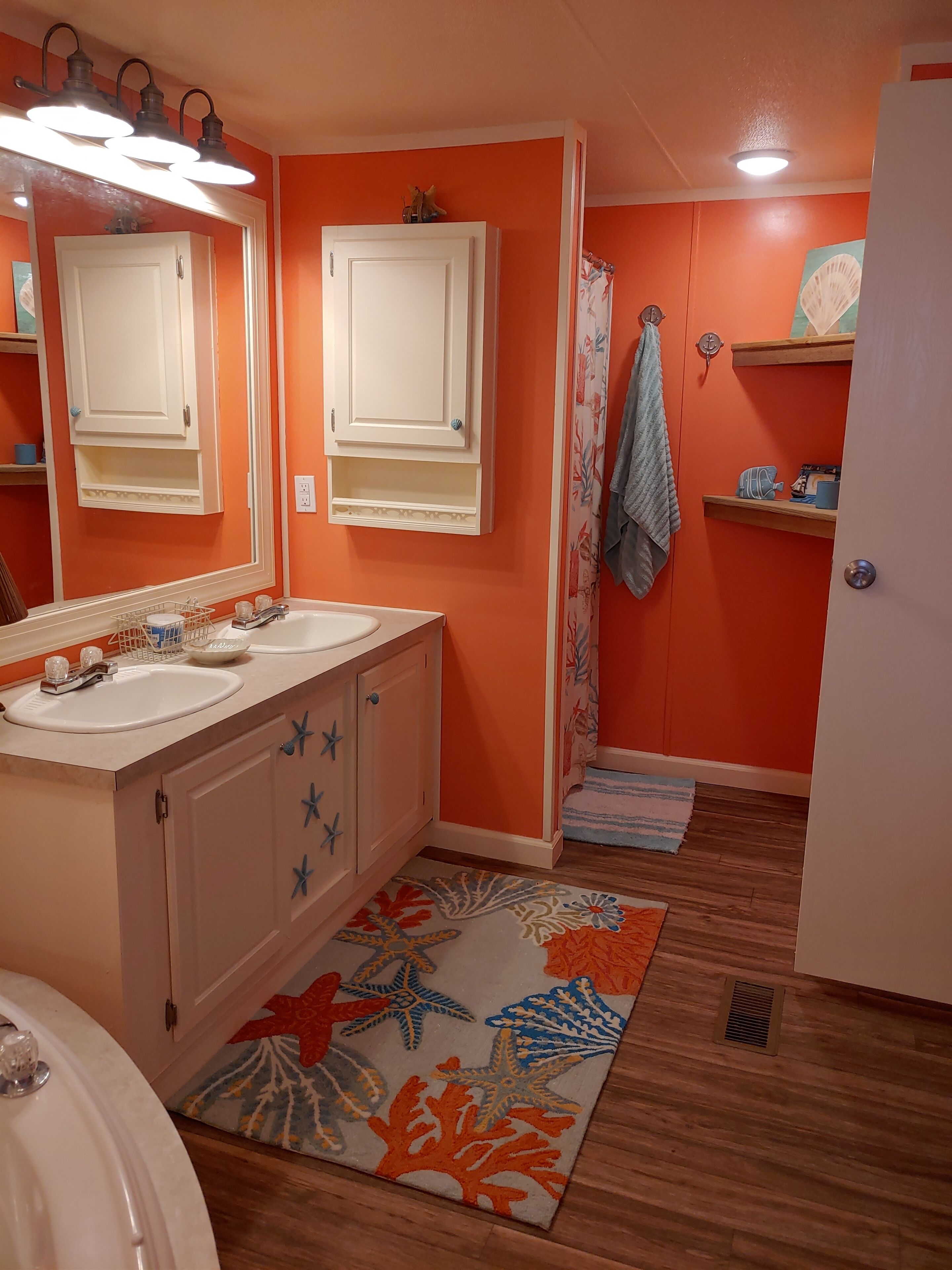 A bathroom with two sinks, a mirror, a cabinet, a shower curtain, and a rug.