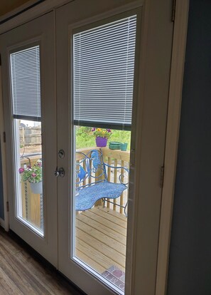 A wooden deck with a metal bench and potted plants.