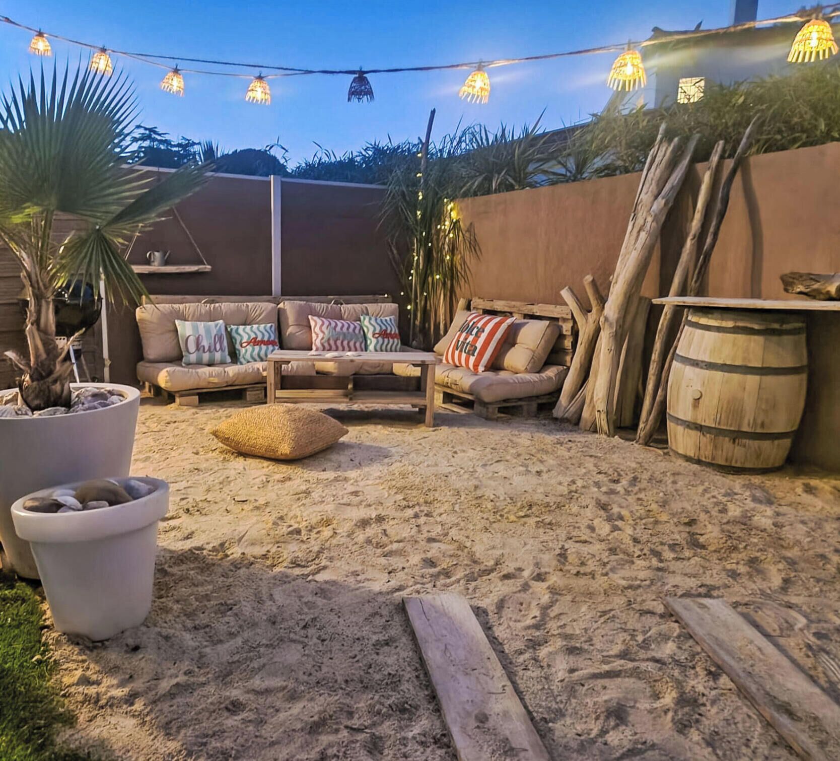 An outdoor seating area with a sofa, cushions, and a wooden table.