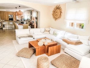 A modern living room with a sectional sofa, a wooden coffee table, and woven poufs. - La pinède by Interhome (Thezan les Béziers)