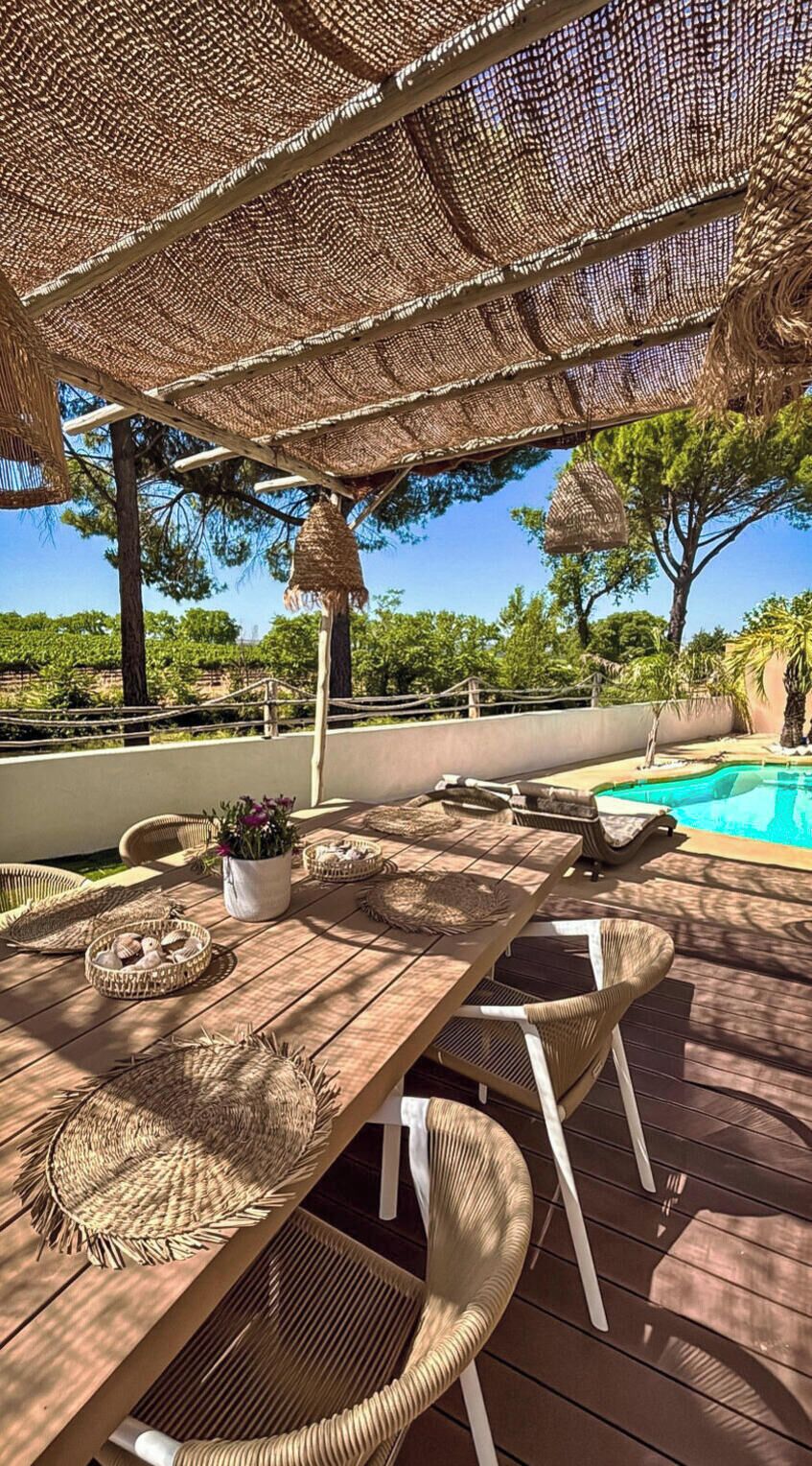 An outdoor dining area with a pool, wicker furniture, and a pergola.