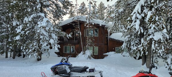 A wooden cabin surrounded by snow-covered trees.