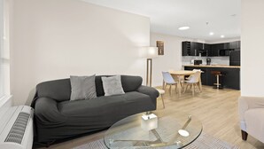 Ein modernes Wohnzimmer mit einer Couch, einem Glastisch und einem Essbereich mit Stühlen.