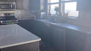 Una cocina moderna con armarios de madera oscura, electrodomésticos de acero inoxidable y un amplio ventanal que proporciona luz natural.