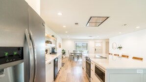 A modern kitchen with a stainless steel refrigerator, white cabinetry, and a central island. - Modern Waterfront Home on the Llano Arm of LBJ - Great for All Ages! (Kingsland)