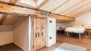 A loft bedroom with a skylight, wooden beams, a white bed, and a small white refrigerator. - Apartment "Casa Sicina Albina" with Mountain View, Wi-Fi & Balcony (Valfloriana Sicina)