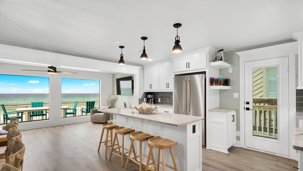 Una cocina moderna con una isla grande, taburetes de bar y vistas al océano.