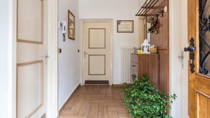 Un pasillo con suelo de madera, una puerta con un cuadro en el marco, un radiador y una planta.