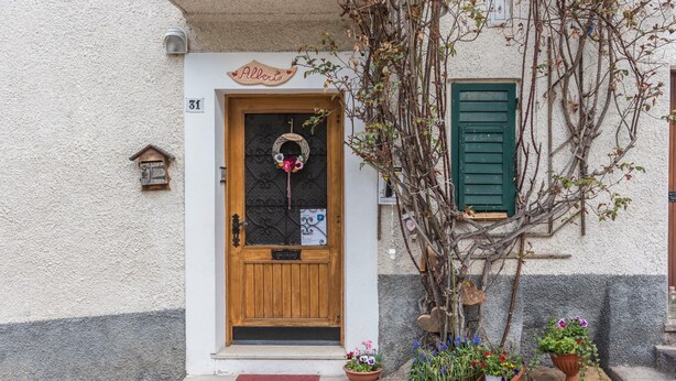 Un edificio con una puerta de madera, un cartel encima y el número 31 en la pared.