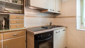 Una cocina con estufa, horno, pileta y alacenas.