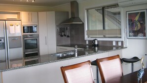 A modern kitchen with stainless steel appliances, a granite countertop, and a dining area with wooden chairs.