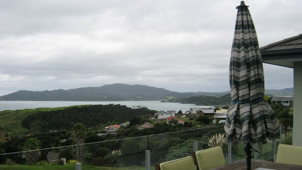 A dining area with a table and chairs, overlooking a scenic view of a lake and hills.
