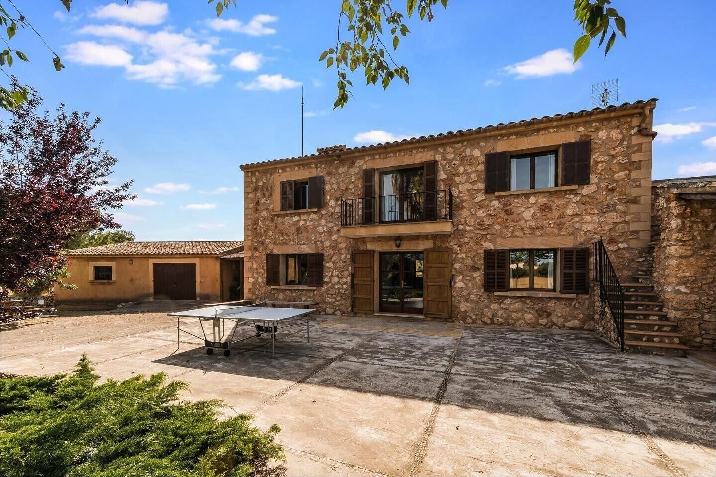 Un bâtiment en pierre doté d’une cour, d’une table de ping-pong et d’un escalier.