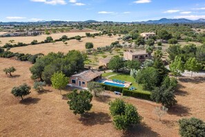 Una villa con piscina, rodeada de árboles y campos.