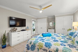 A bedroom with a bed, a television, a ceiling fan, a dresser, and a potted plant. - Private Beach Villa: Modern Luxury at Crystal Sand (Siesta Key)