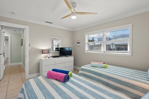 A bedroom with two beds, a TV, a ceiling fan, and a window with blinds. - Private Beach & Gulf-Front Pool Modern Free-Standing Villa at Crystal Sands (Siesta Key)