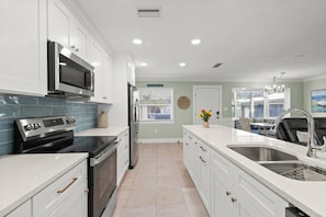 Una cocina moderna con armarios blancos, electrodomésticos de acero inoxidable y una isla grande con un lavamanos.