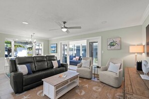 A spacious living room with a black leather sofa, a beige armchair, and a wooden coffee table. - Private Beach Villa: Modern Luxury at Crystal Sand (Siesta Key)