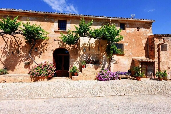 A traditional building with a stone facade, a central doorway, and potted plants.