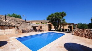 Ein Pool mit Liegestühlen, einer Pergola und Steinmauern.