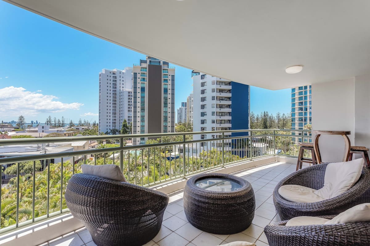 A balcony with wicker furniture and a view of tall buildings.
