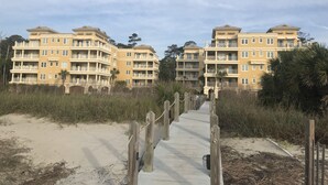 A beachfront hotel with multiple balconies and a sandy walkway leading to the entrance. - 3 bedroom,baths, Pool, Land Trans from Dock, 4 passenger golf cart included! (Daufuskie Island)
