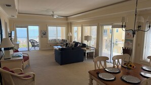 A spacious living area with a sofa, dining table set for four, and a balcony with a view. - 3 bedroom,baths, Pool, Land Trans from Dock, 4 passenger golf cart included! (Daufuskie Island)