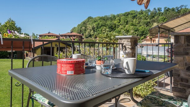 Une table de patio avec un récipient rouge, une tasse blanche et un verre.