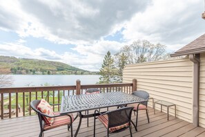 A wooden deck with a metal table and chairs, overlooking a lake and hills. - Cozy Cove Retreat w/ Deck & Fireplace (McHenry)