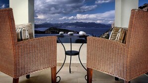 Een rieten lounge stoel en tafel met uitzicht op bergen en een meer.