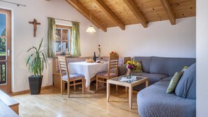 Un comedor con techo de madera, una mesa con sillas, un sofá y una planta en maceta.