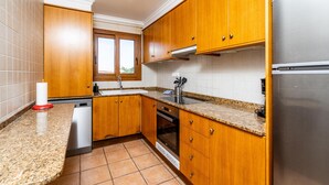 Eine Küche mit Holzausstattung, einem Edelstahlkühlschrank, einem Geschirrspüler und einem Fenster mit Blick.