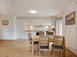 A modern kitchen with white cabinets, a dining table with chairs, and a coffee machine.