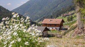A wooden house with a sloped roof, a small wooden structure, and a wooden fence. - Apartment "Radlspitz - Maurerhof" with Mountain View, Wi-Fi & Garden (Sarntal - Südtirol (BZ))