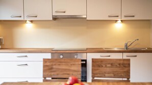 Una cocina moderna con armarios blancos, encimera de madera y un lavamanos.