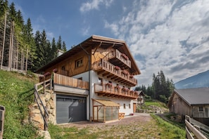 A multi-story wooden chalet with balconies, a garage, and a covered patio area.