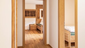 Un pasillo que lleva a un dormitorio con una cama de madera, una mesita de noche y un aparador.