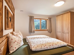 A bedroom with a bed, pillows, a window with curtains, and wooden furniture.