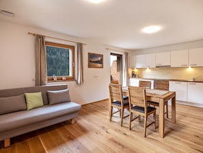 Un salon confortable avec un canapé, une table à manger avec des chaises, un coin cuisine avec des placards et une fenêtre avec des rideaux.