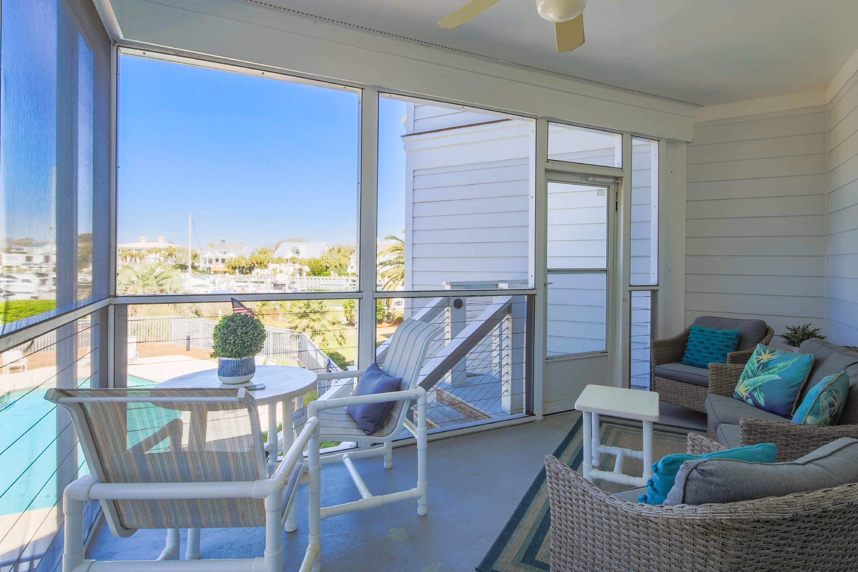 Ein Balkon mit Blick auf eine Marina, Korbmöbel und ein kleiner Tisch mit einem Blumentopf.
