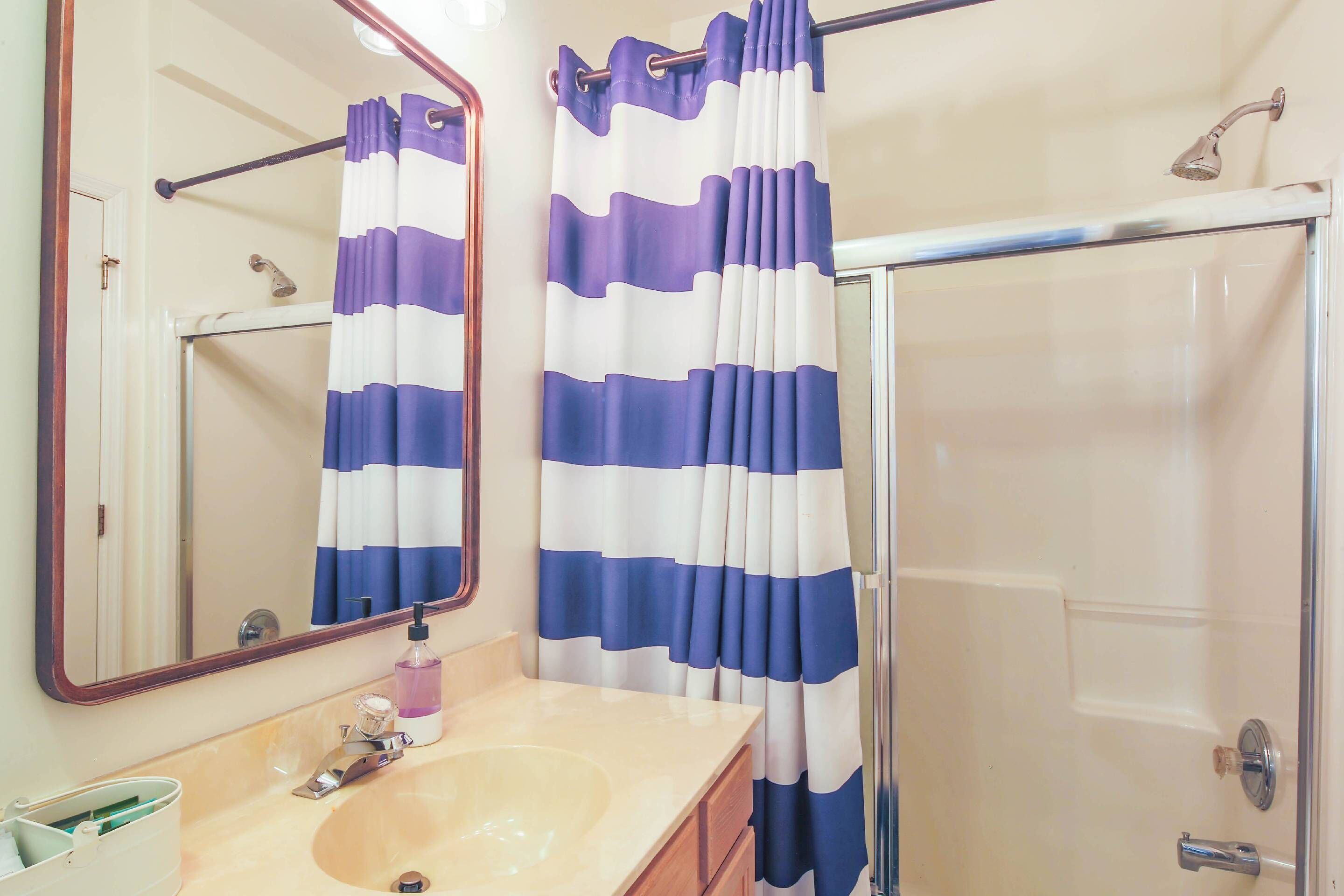 A bathroom with a sink, mirror, and shower curtain.